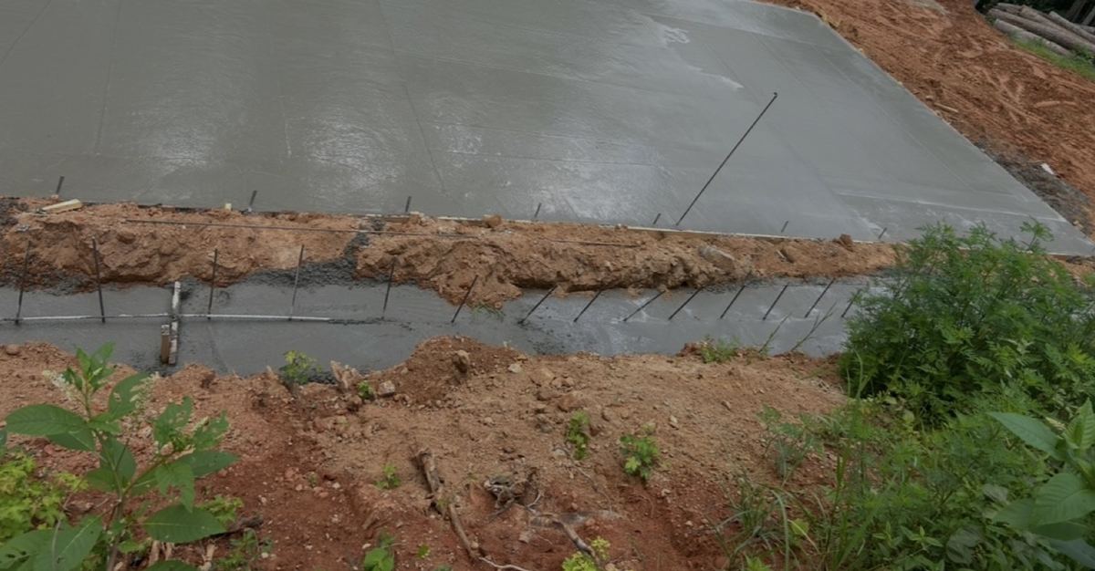 Smooth concrete slab with rebar along the edge and a poured footing trench below