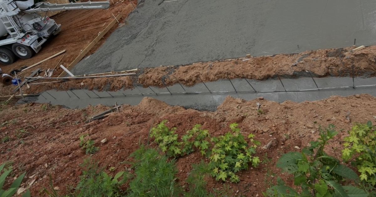 Slab and footing pour on a sloped site, with a concrete truck parked uphill