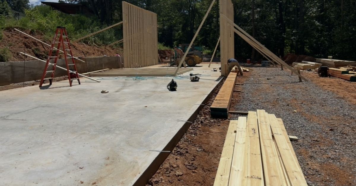 Cured concrete slab with wall framing going up beside it